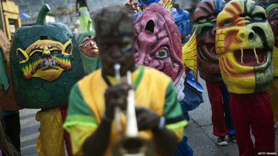 Reveler in papier mache masks perform during the first day of 2015 National Carnival Parade.