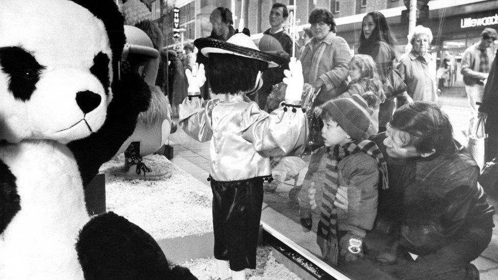 People look in shop window at Christmas display figures