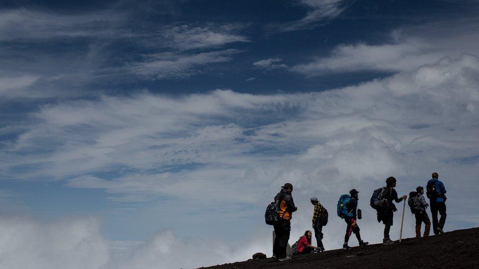 Six climbers hike along a trail to the summit of Mount Fuji on 2 July 2015, with blue skies in the background.