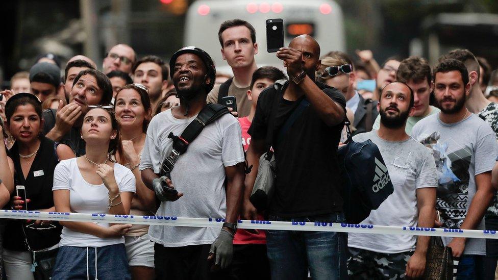 Pedestrians stop to watch as a man scales the all-glass facade of Trump Tower using suction cups