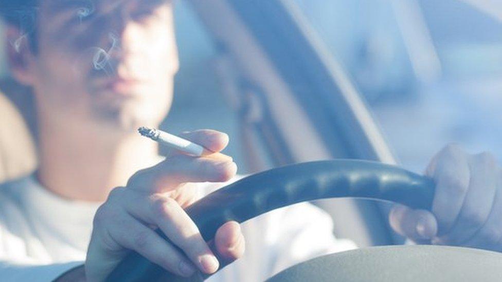 A man smoking in a car