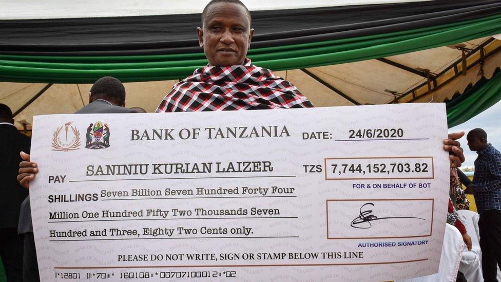 Tanzanian small-scale miner Saniniu Kuryan Laizer, 52, poses with the enlarged cheque copy from the government after selling two of the biggest of the country's precious gemstones, Tanzanite, during the ceremony for his historical discovery in Manyara, northern Tanzania - 24 June 2020