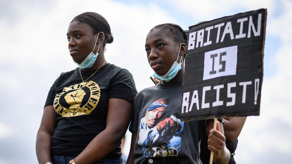 BLM protestor holding a Britain is racist sign.