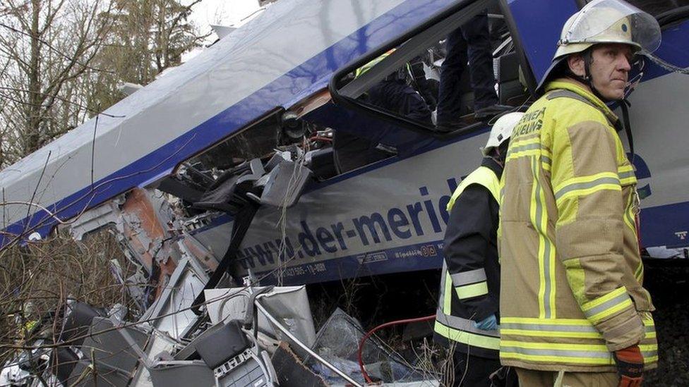 Rescuers stand in front of a carriage at the site of the two crashed trains