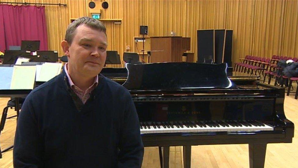 Michael Garvey stands by a grand piano