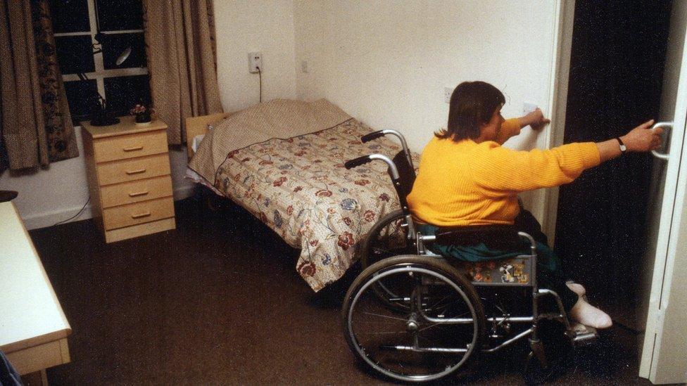 A woman pulling herself out her room in her wheelchair