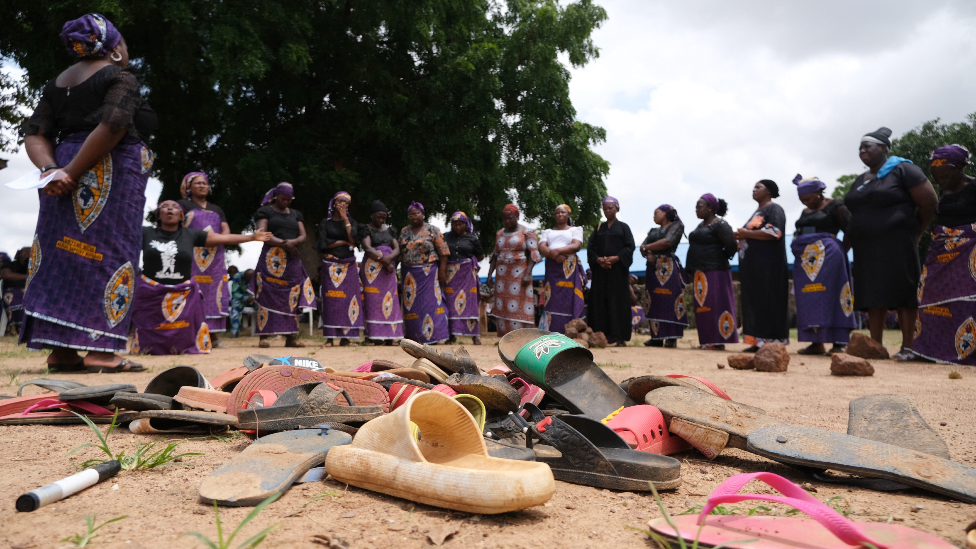 Parents of kidnapped students from Bethel Baptist High School, in Nigeria's Kaduna state, stand by shoes left behind after the attack - July 2021