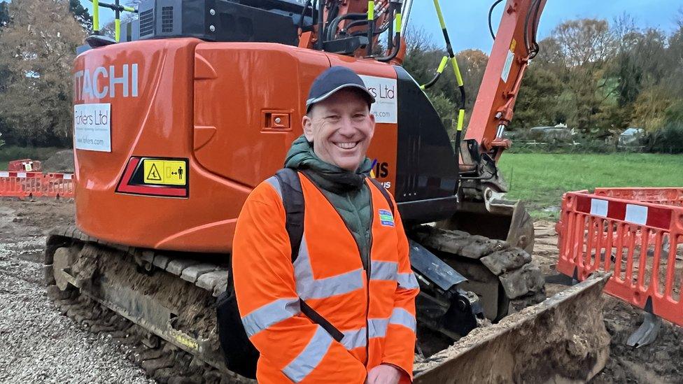 Man smiling in front of digger