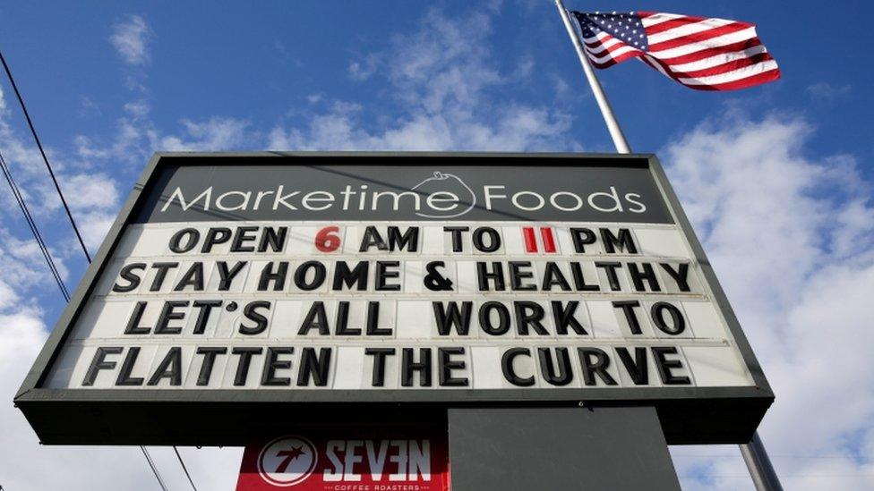 A market marquee in Seattle, Washington reads "stay home and healthy, let's all work to flatten the curve"