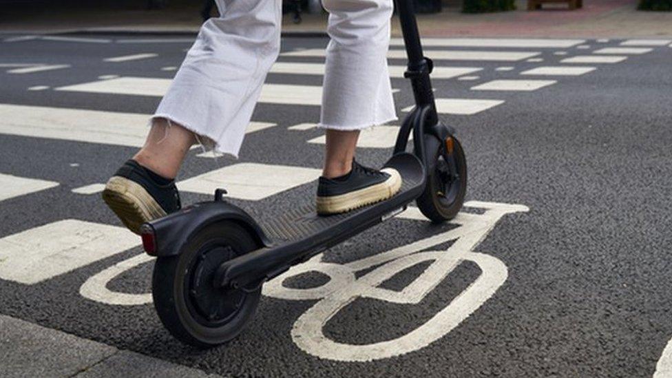 Person riding new e-scooter on road.