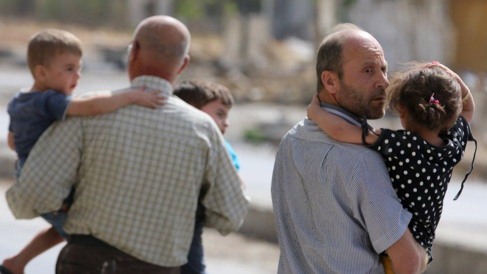 Men carry children away from a damaged site after airstrikes on the rebel held al-Qaterji neighbourhood of Aleppo, Syria September 21, 2016