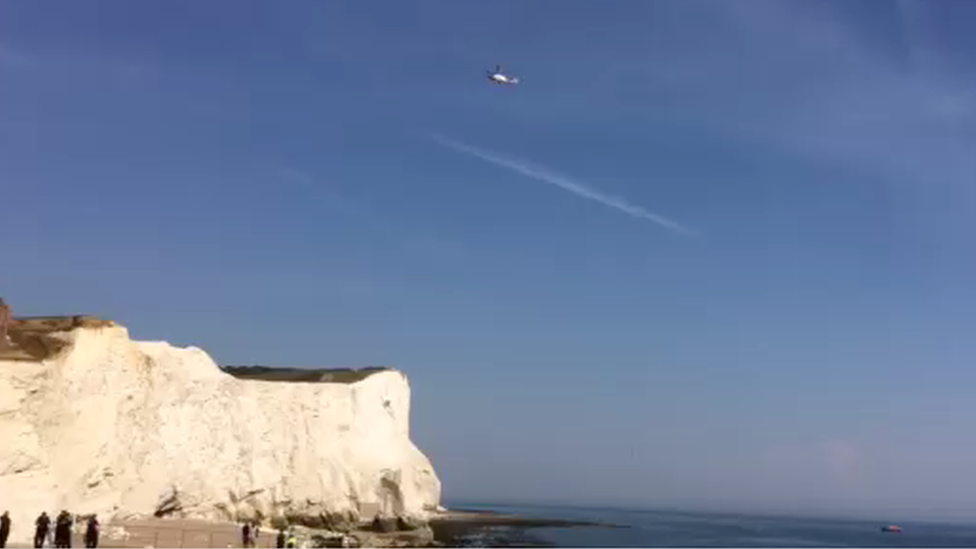 A helicopter hovers over the fallen cliff at Seaford Head, East Sussex