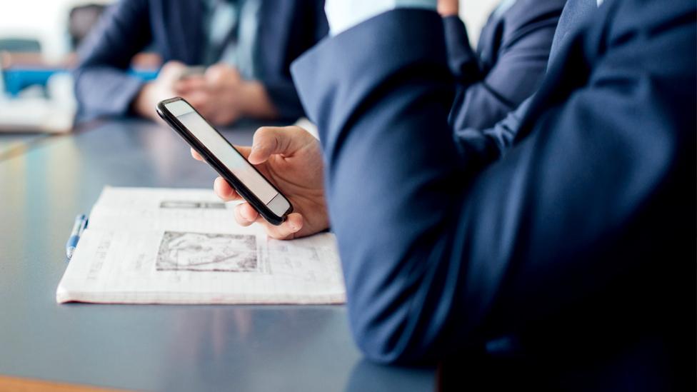 Stock image of a student looking at a mobile phone in a classroom