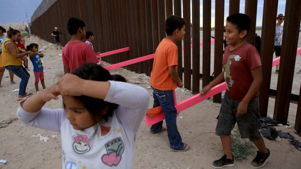 Children play on seesaws at the Mexican border