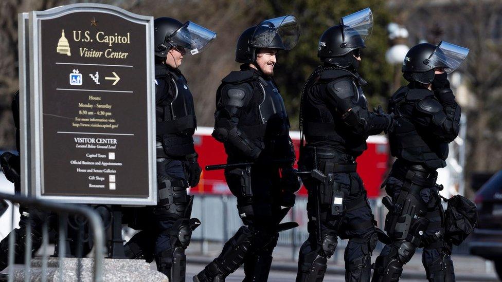 US Capitol Police officers in riot gear walk through the grounds around the US Capitol on the day before the inauguration