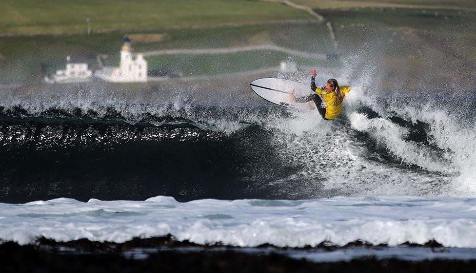 A surfer rides a wave