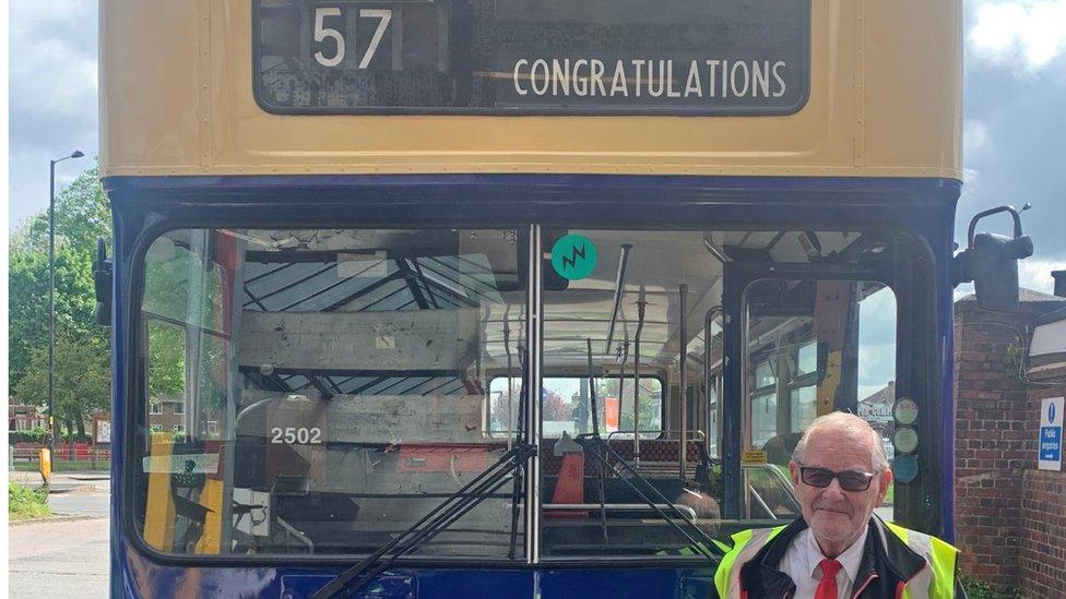 A driver in front of a bus