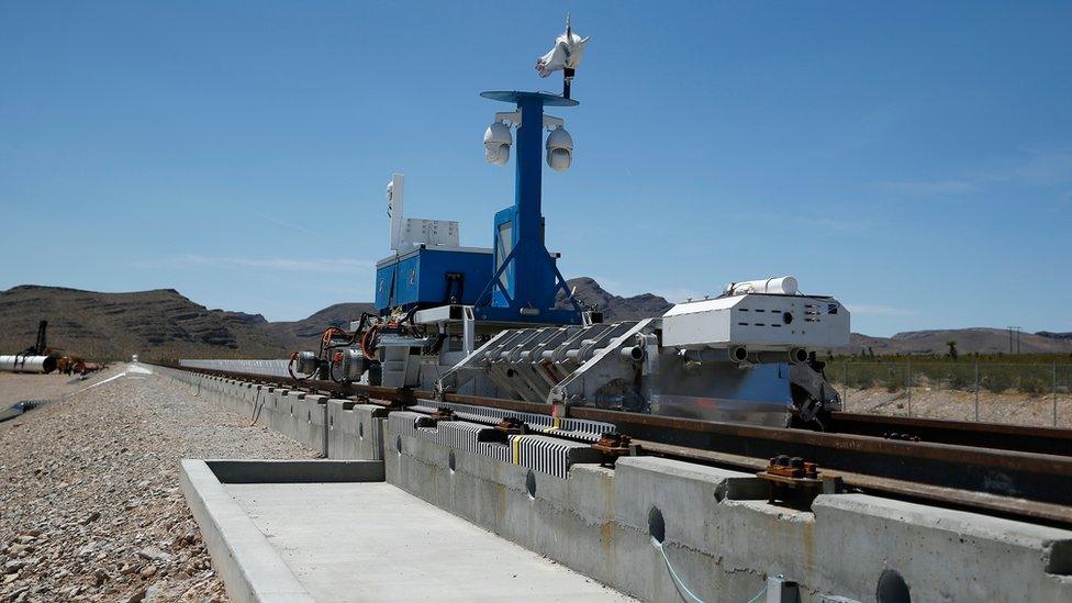 A recovery vehicle and test sled sit on a track after a test of a Hyperloop One propulsion system