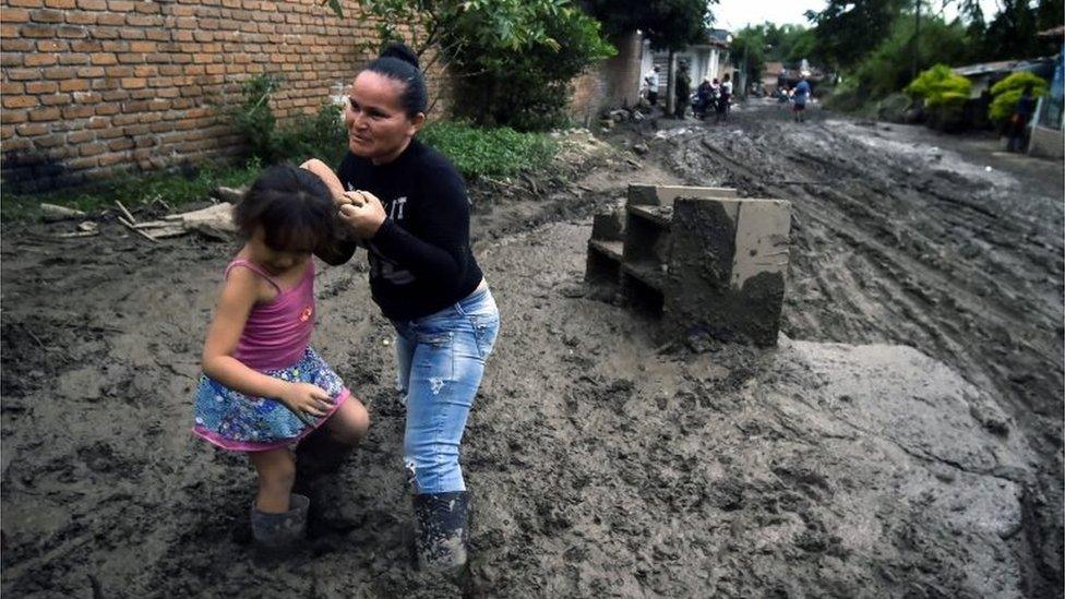 A woman and her daughter struggle to walk along a muddy street, after a mudslide due to heavy rains affected Corinto in Cauca department, southwest Colombia on November 8, 2017