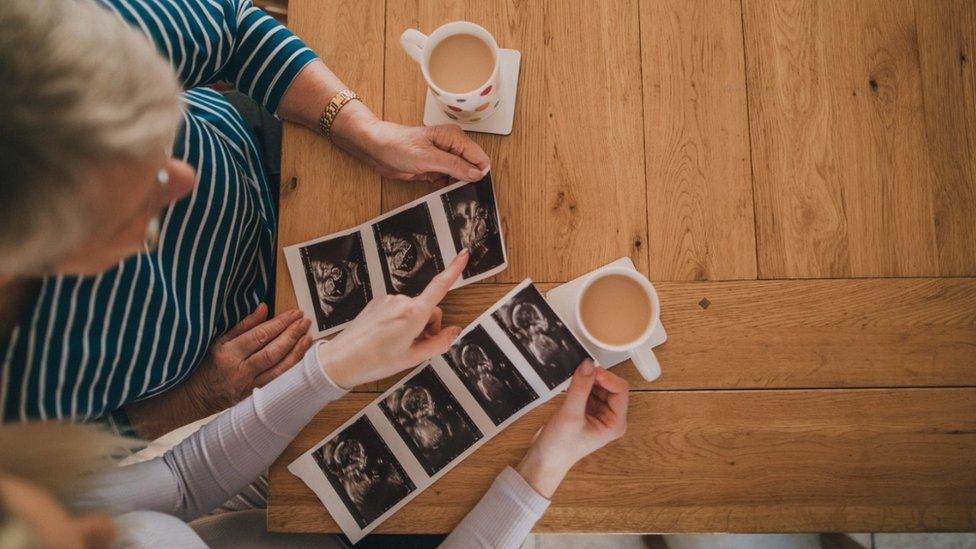 Nan and niece viewing the new baby scan photos with a cup of tea in the dining room.