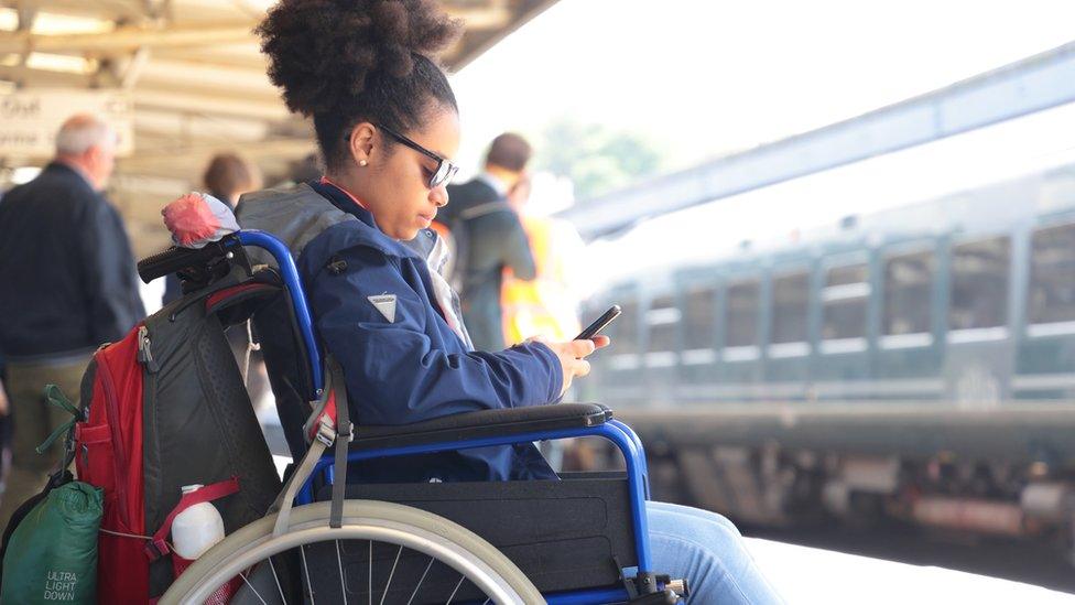 Disabled woman at train station (stock photo)