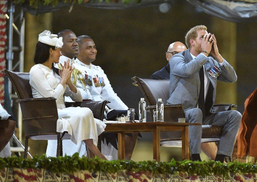 Prince Harry drinks kava as his wife Meghan, the Duchess of Sussex looks on at a traditional welcome ceremony after they arrived in Suva, Fiji on October 23, 2018