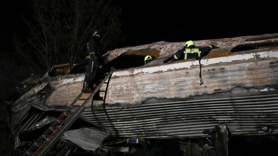 A firefighter climbs up a ladder near the damaged train