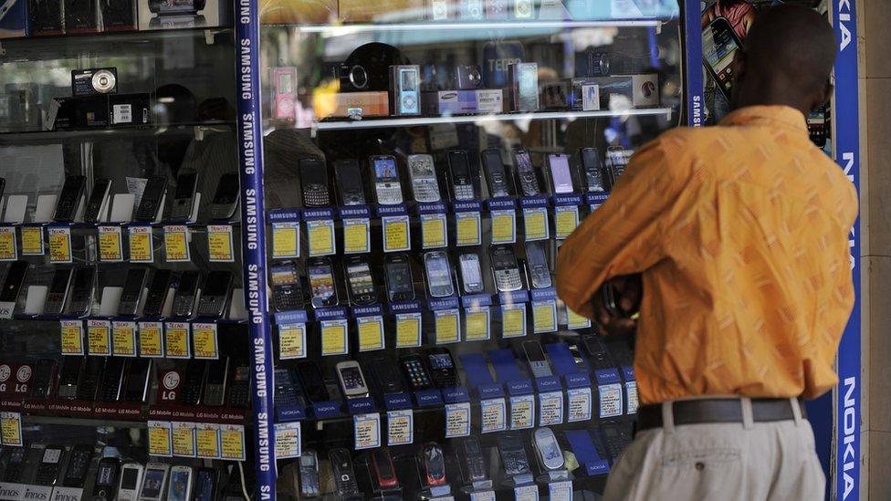 A man stands in front of a shop window displaying mobile phones on 1 October 2012 in Nairobi, Kenya.