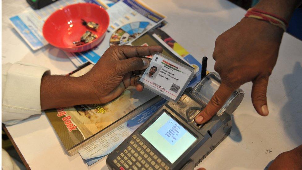 An Indian visitor gives a thumb impression to withdraw money from his bank account with his Aadhaar or Unique Identification (UID) card during a Digi Dhan Mela