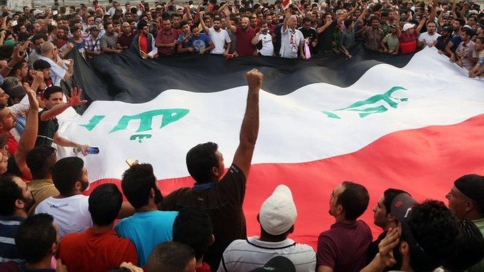 Protesters chant anti-Iraqi government slogans as they carry a large national flag during a protest against against corruption and the lack of government services in Tahrir Square in central Baghdad, Iraq, Friday, 31 July 2015