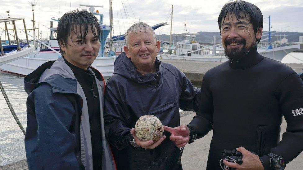 Researchers posing with the cannonball