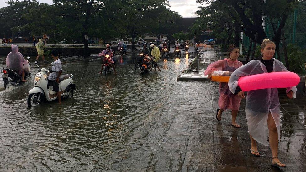 Tourists use rubber rings to cross a flooded road on Koh Samui, Thailand, 5 January 2017