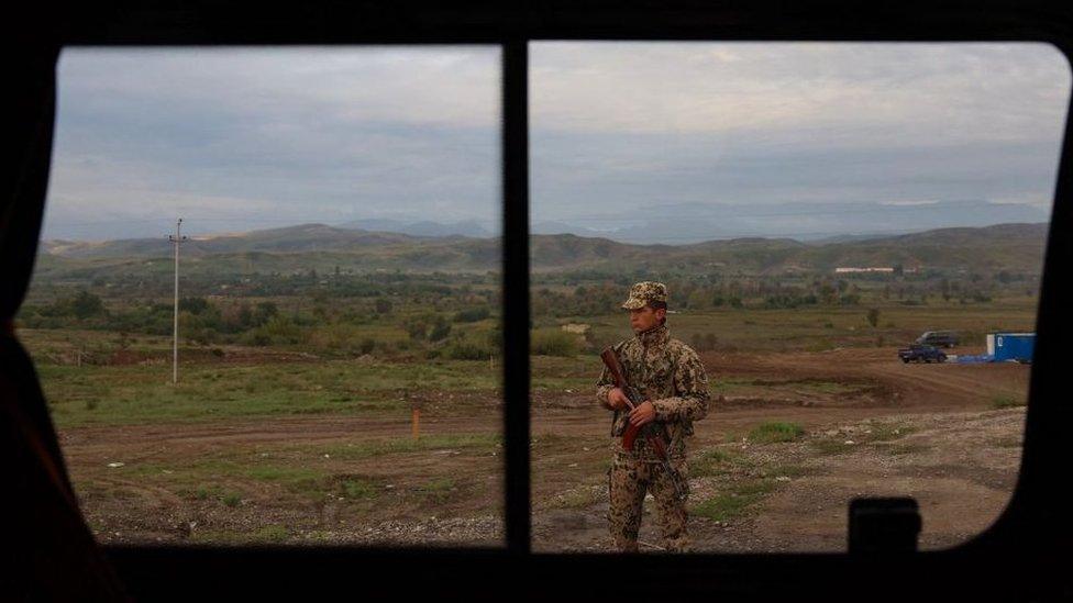 An Azerbaijan police officer stands guard at a checkpoint along the border road in Agali, Zangilan district, on September 26