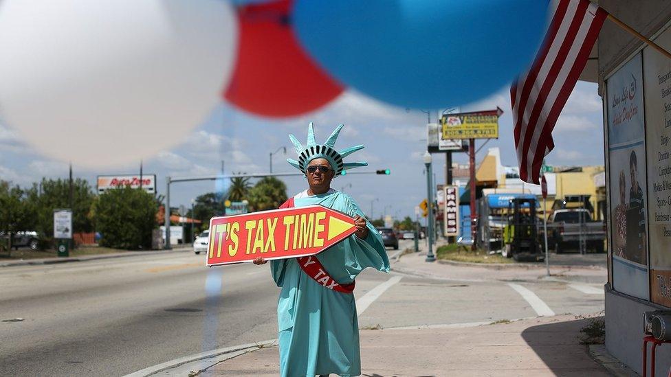 Armanda La Rosa directs people to the Liberty Tax Service office as the deadline to file taxes looms on April 15, 2016 in Miami, Florida.