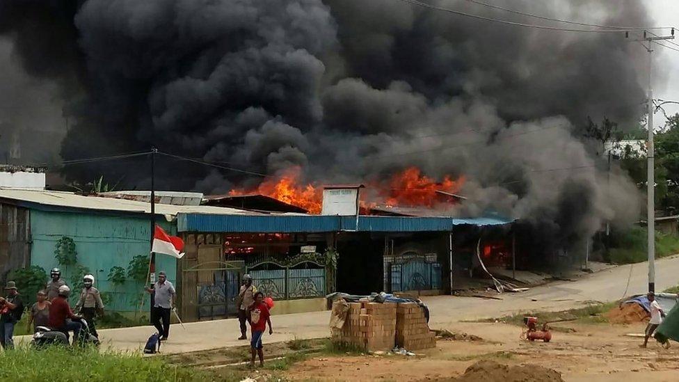 A building, set on fire by rioting demonstrators, is seen in Sorong