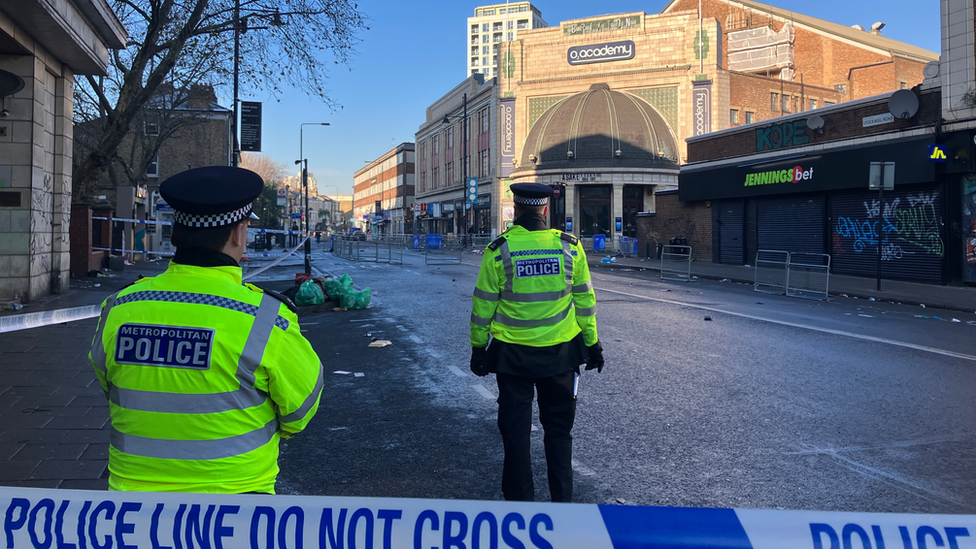 View of two police officers behind a cordon, in front of the venue.