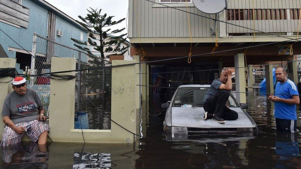 Inhabitants stand in flood water in front of a house flooded in Juana Matos, Catano, Puerto Rico, on 21 September 2017