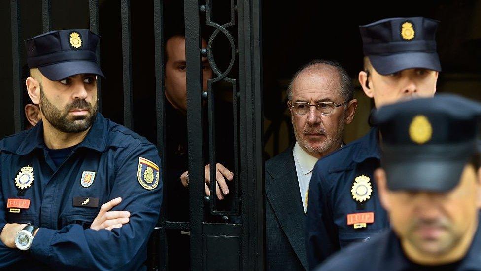 Former IMF head and former Spanish Economy minister Rodrigo Rato (C) is surrounded by policemen as he leaves his office, on 17 April 2015 in Madrid