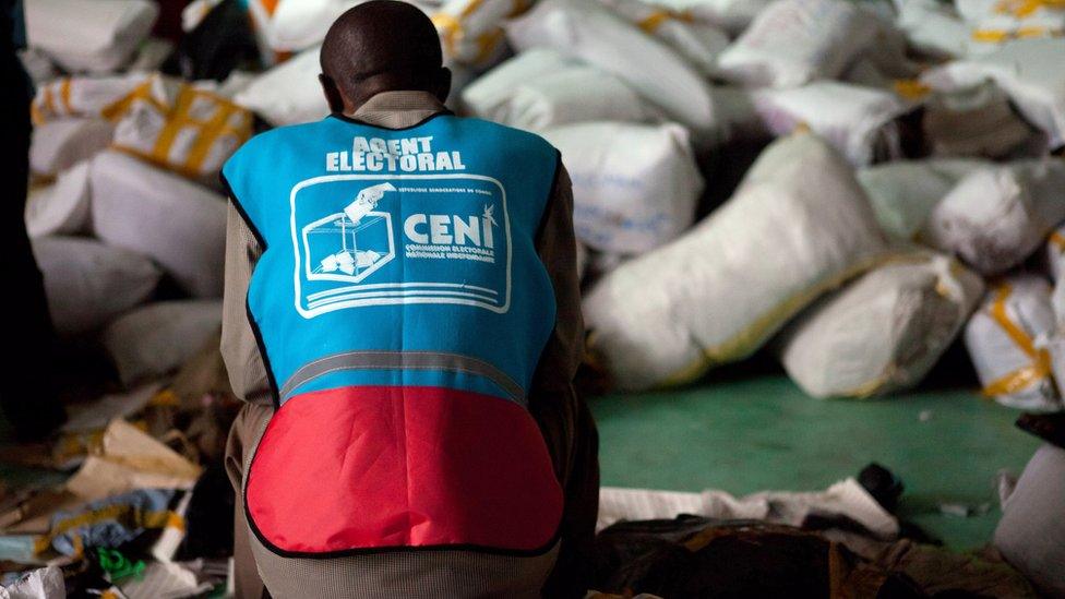 An electoral agent of the National Independent Electoral Commission (CENI) sits on a bag of ballot papers in a warehouse in Kinshasa on December 3, 2011