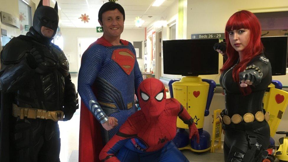 A group in costume as Batman, Superman, Spiderman and Black Widow