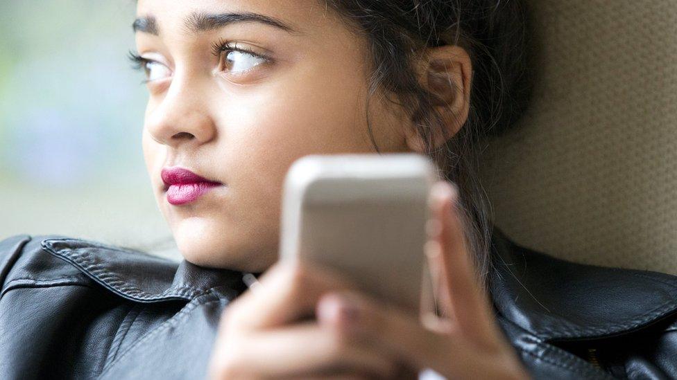 File photo: A young girl holding a mobile phone