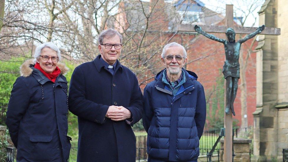 The Reverend Canon Andrew Shipton and churchwardens Nick Glover and Christine Willoughby in the garden of remembrance at All Saints Church, with the restored sculpture in the background