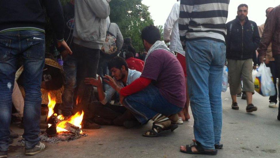 Refugees and migrants try to keep warm in the early on Tuesday morning in the Serbia border town of Presevo