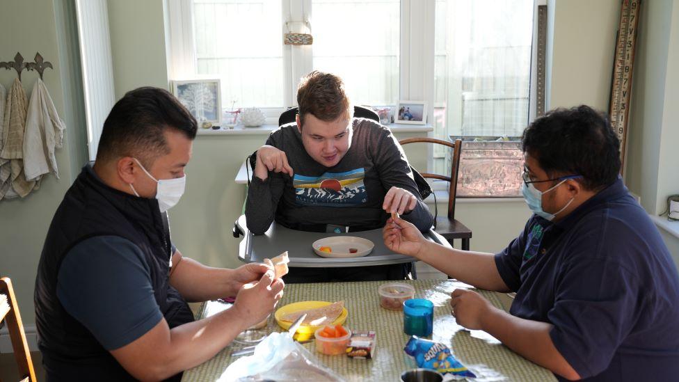 Oscar and his carers at a table