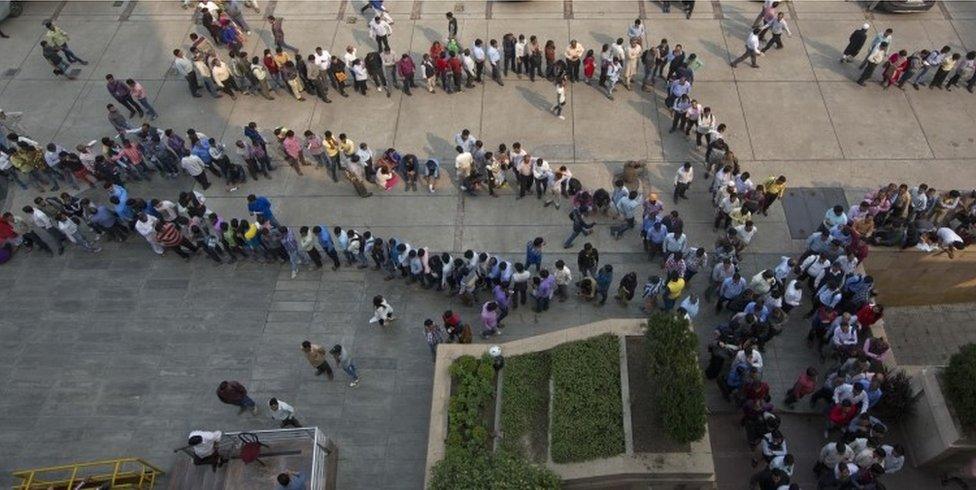 Indians stand in queues to exchange or deposit discontinued currency notes outside an Axis Bank branch in central New Delhi, India.