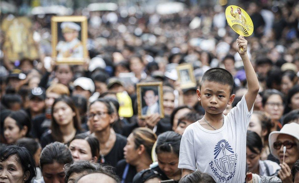 A Thai well-wisher holds a picture of the King Bhumibol Adulyadej as they wait for the procession to move the body of the King outside of the Siriraj Hospital in Bangkok, Thailand, on 14 October 2016.