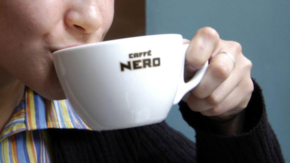 Woman drinking out of a Caffe Nero cup