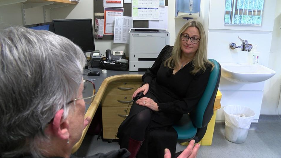 Blonde haired lady talking to a patient in a GP surgery consultant room