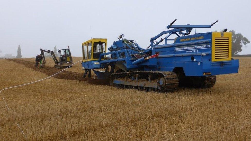 Trenching machine at work in field