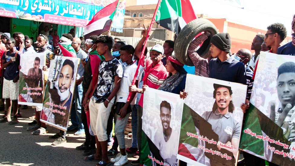 Sudanese demonstrators carry posters of killed protesters in Khartoum - 30 December 2021